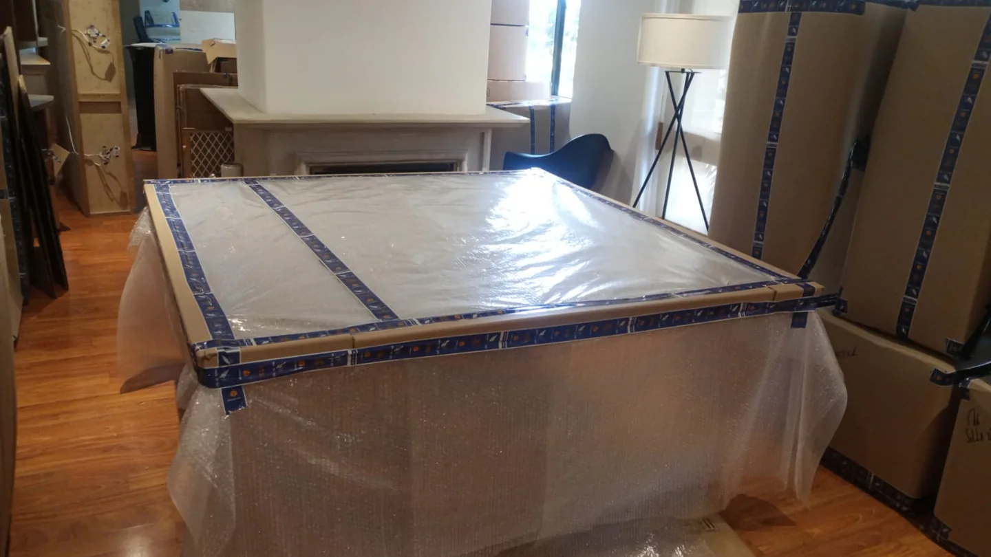 Mesa protegida con cartón y plástico de burbujas durante el empaque